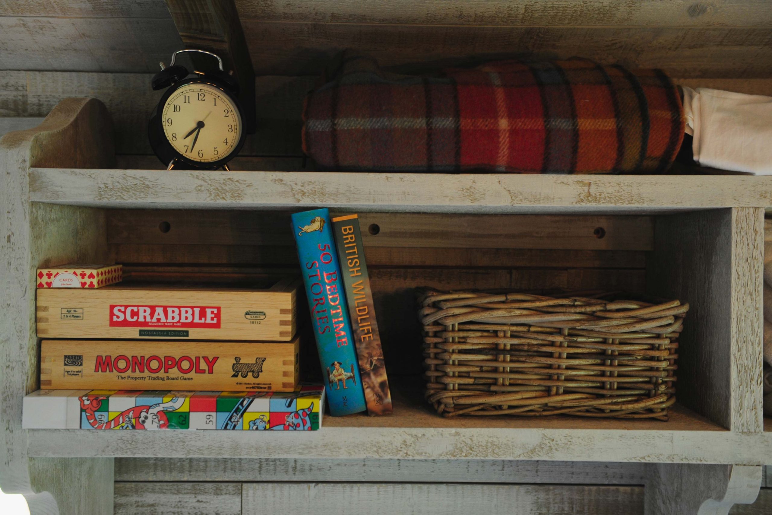 Board games and story books on a shelf inside one of the cabins at Loose Reins