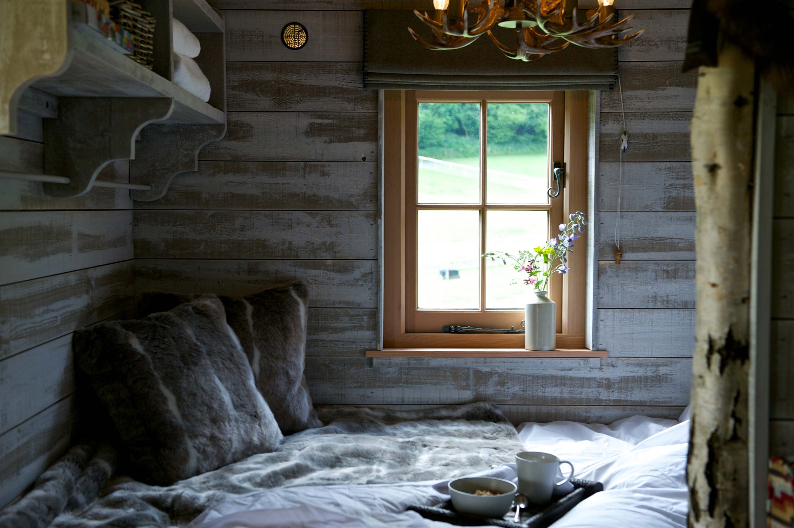 The bedroom of a Loose Reins' cabin with cosy bedding and a tray with breakfast bowls