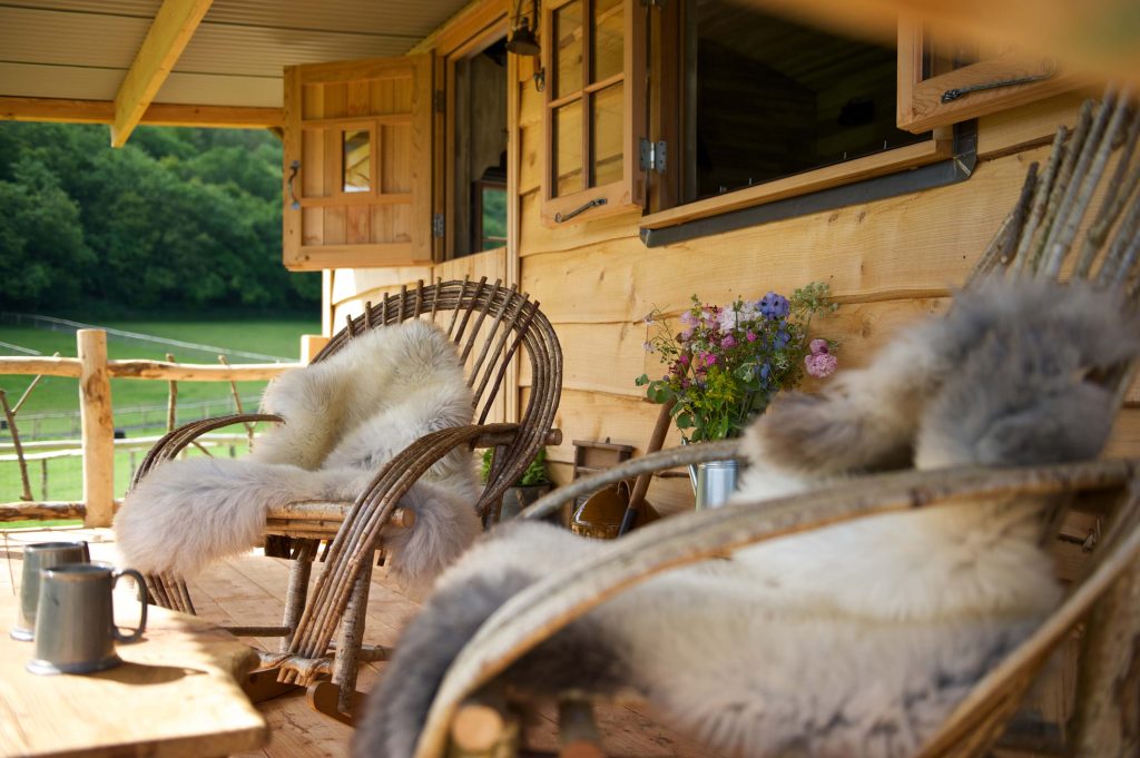 Cosy blanket covered rocking chairs on the porch of a cabin at Loose Reins