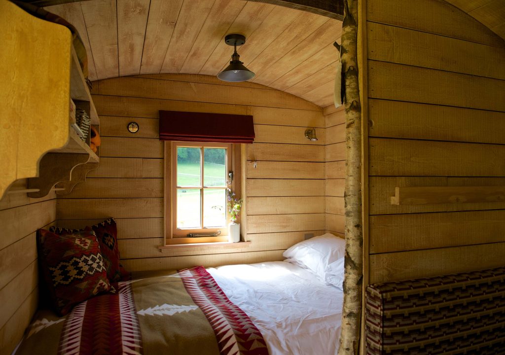 The bedroom area inside one of the cabins at Loose Reins complete with cosy blanket and cushions