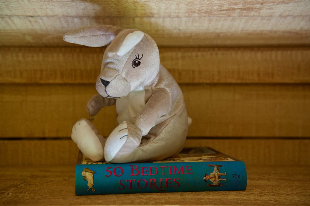 A soft toy and story book on a shelf inside one of the cabins at Loose Reins