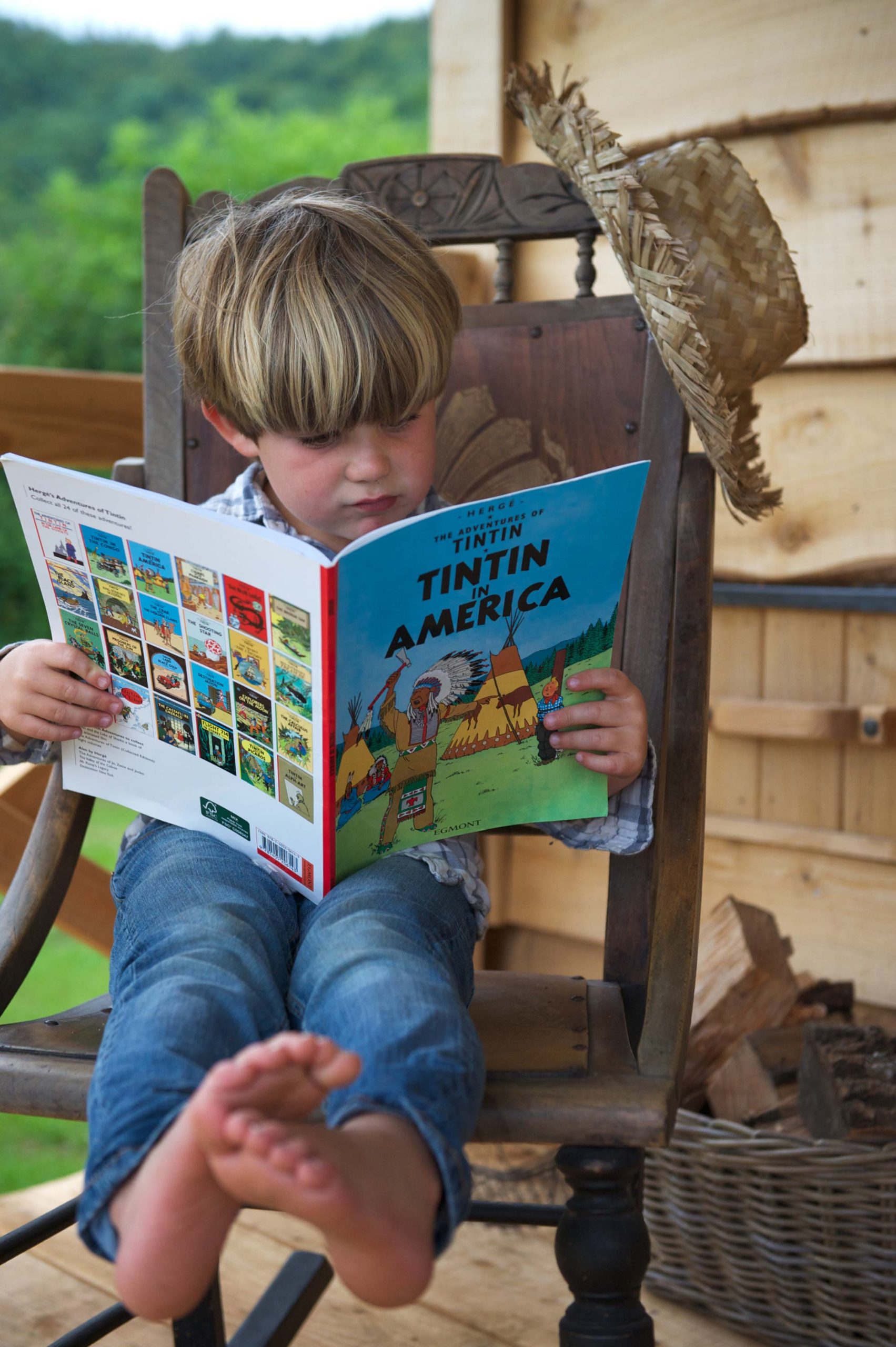 A boy sitting on the cabin porch at Loose Reins reading a book