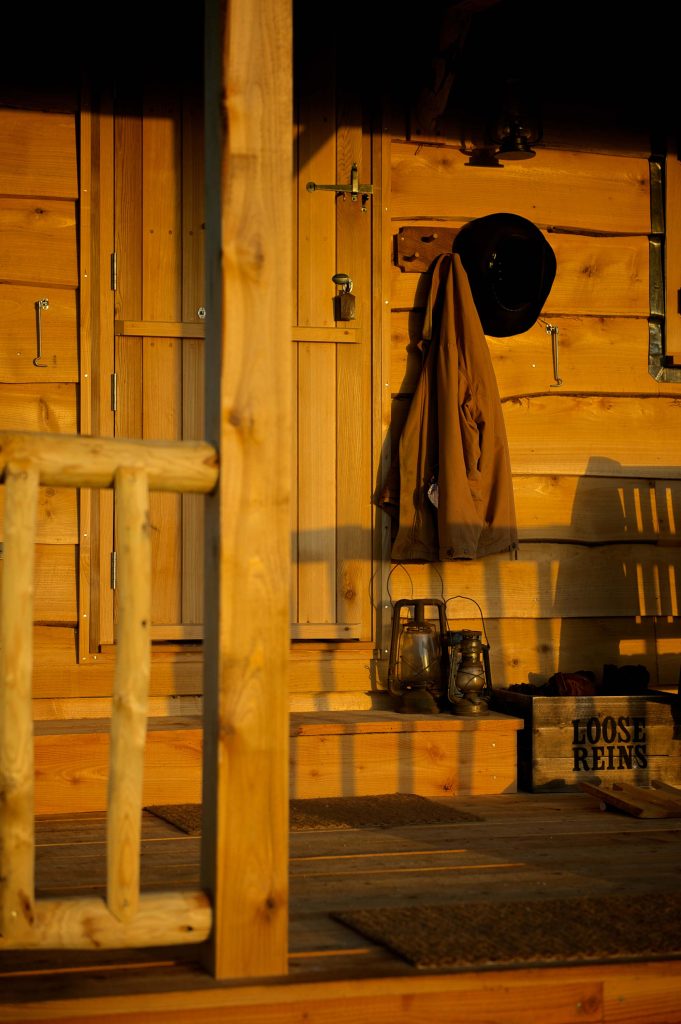A coat and hat hanging on a hook on the porch of a cabin at Loose Reins