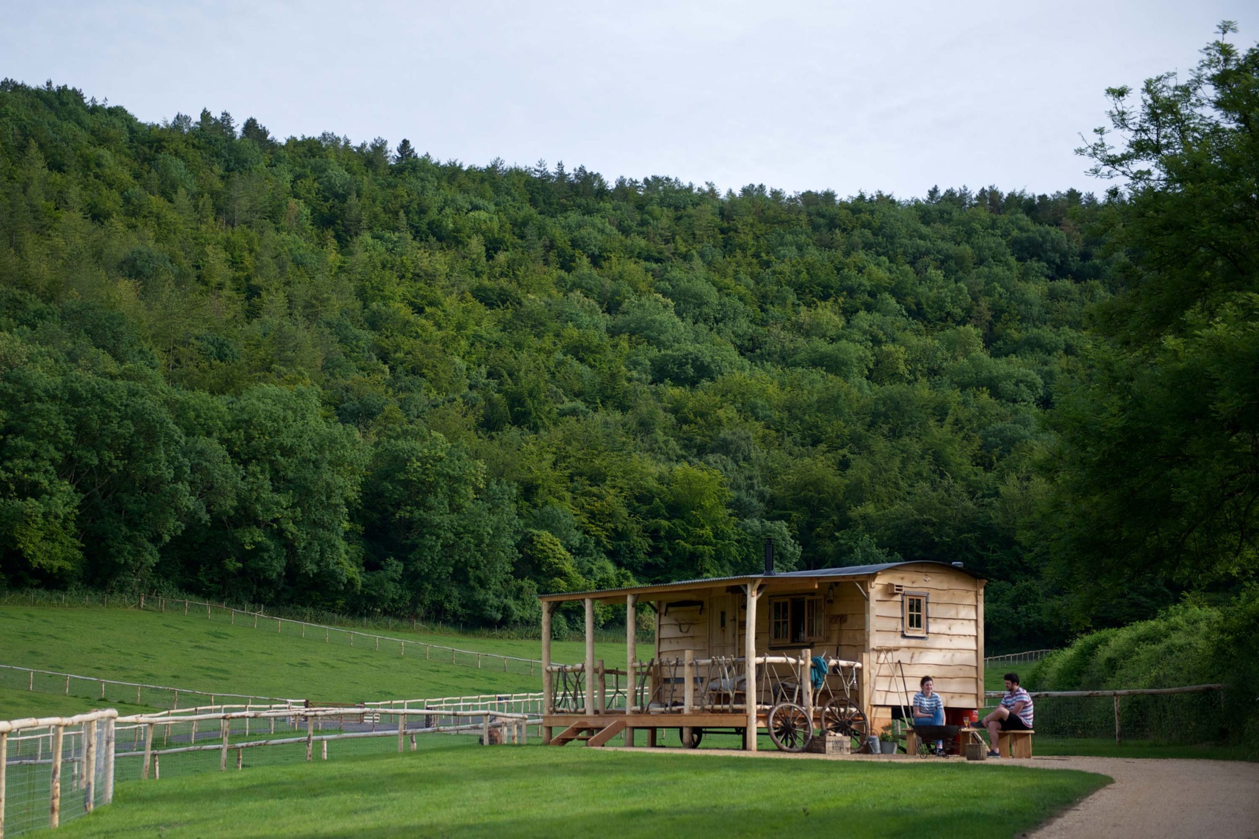 A couple sitting outside one of the cabins at Loose Reins with a lush woodland in the background