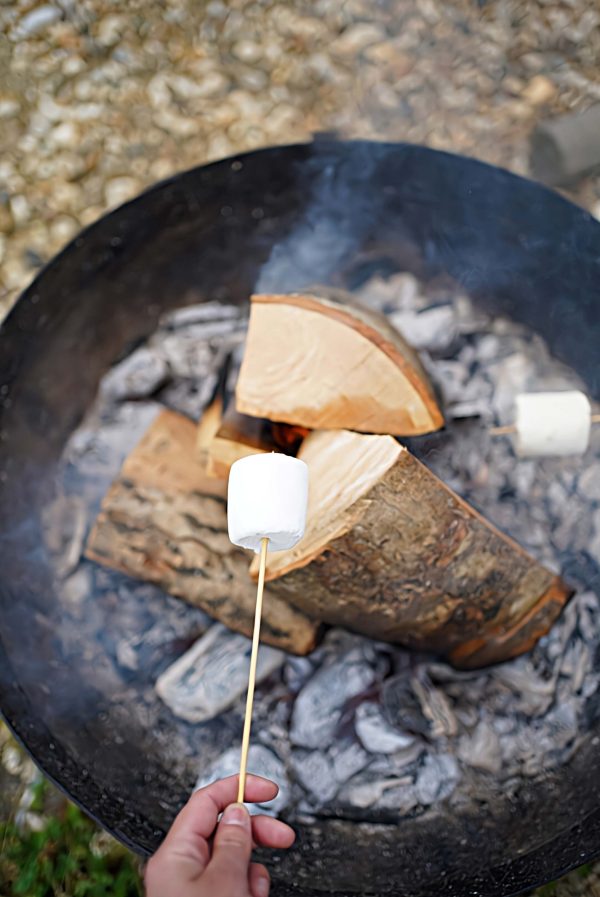 Guests toasting marshmallows over the firepit outside their cabin at Loose Reins