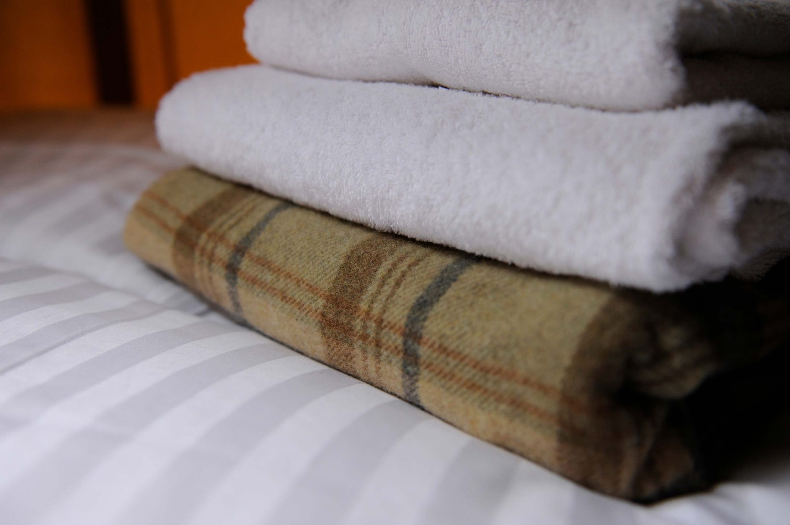 Blankets and towels stacked on one of the beds in lodge at Loose Reins