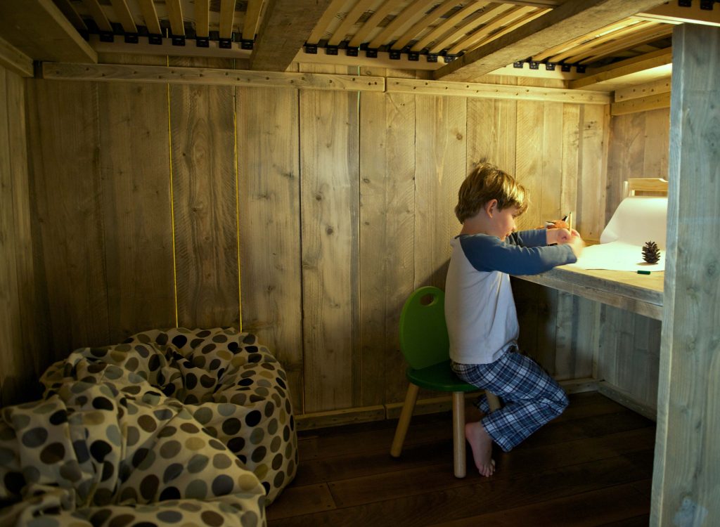 A young boy inside the secret den under the cabin bed in one of the Lodges at Loose Reins