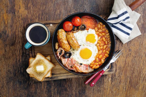 Birds eye view of a dull English Breakfast containing sausages, eggs, bacon, tomatoes and beans.