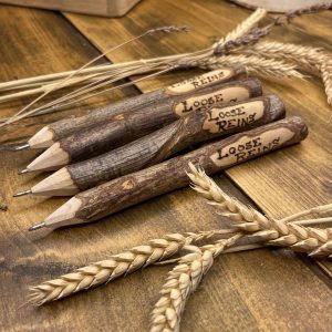 A rustic wooden pen with Loose Reins pyro engraved on the side