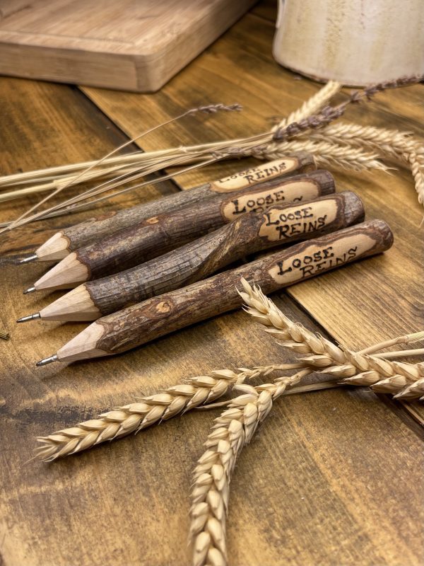 A rustic wooden pen with Loose Reins pyro engraved on the side