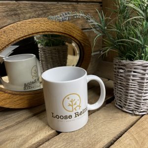 A white Ceramic Mug with the Loose Reins Logo printed on the front