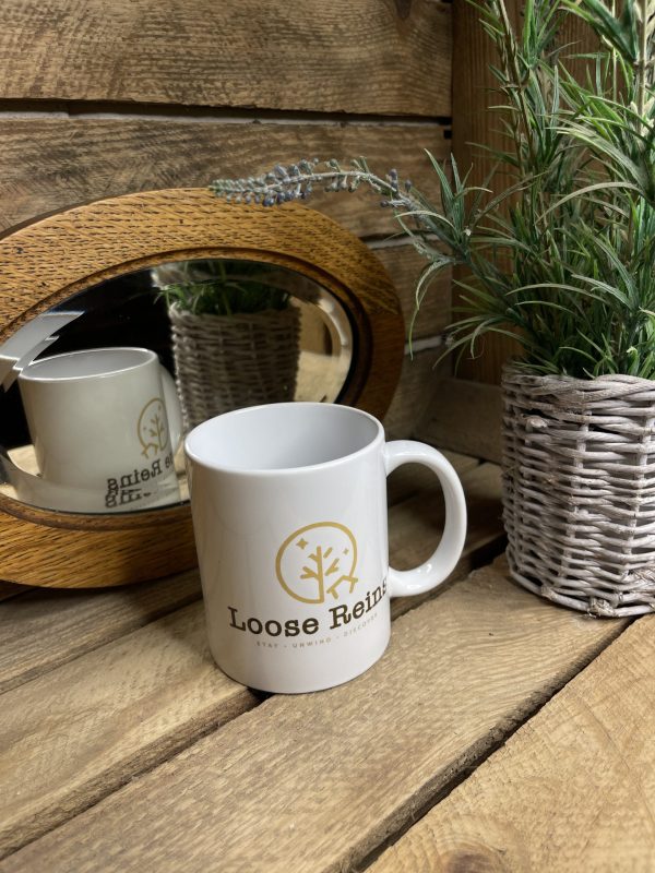 A white Ceramic Mug with the Loose Reins Logo printed on the front